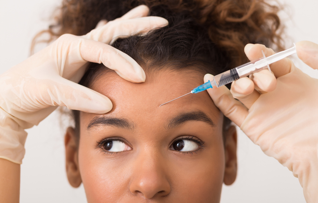 African-american woman getting botox injection in forehead